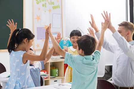 男孩举起红旗教师和小学生在教室里背景