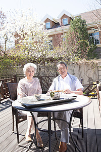 垂直构图高雅70多岁老年夫妇在庭院喝茶高清图片