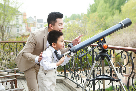 望远镜人父亲和儿子在阳台使用天文望远镜背景