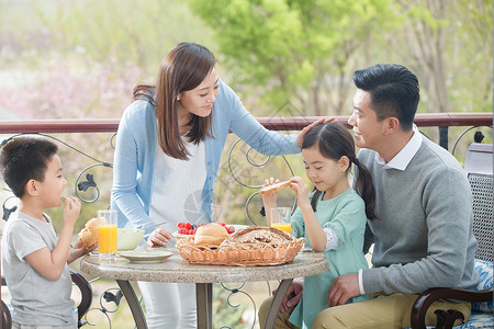 户外果汁幸福家庭在阳台吃早餐背景