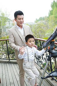 天文望远镜男孩父亲和儿子在阳台使用天文望远镜背景