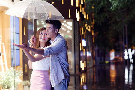下雨打伞情侣下雨天夜里一起逛街的情侣背景