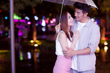 黑夜里的伞下雨天夜里一起逛街的情侣背景