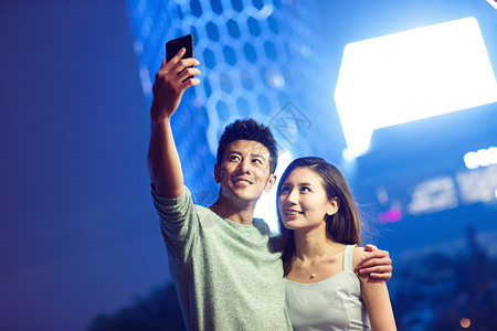 霓虹灯拍照人青年情侣在自拍图片
