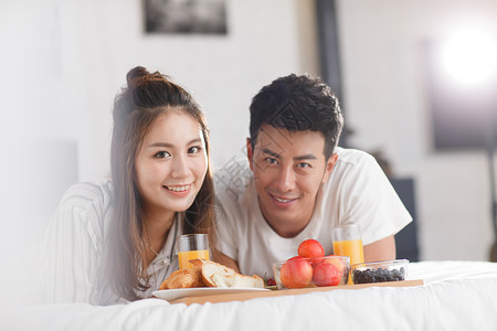 青年情侣在床上吃早餐高清图片