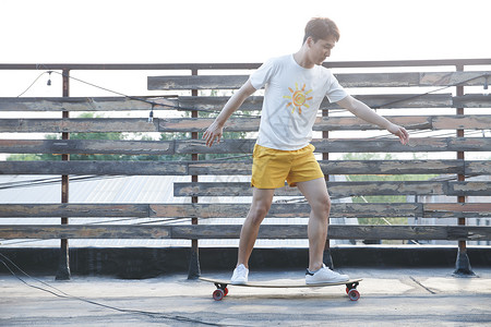屋顶刺激嬉戏的青年男人玩滑板图片