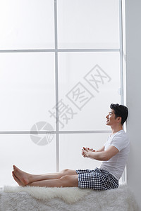 彩色地毯坐着彩色图片家居服青年男人坐在窗户旁边背景