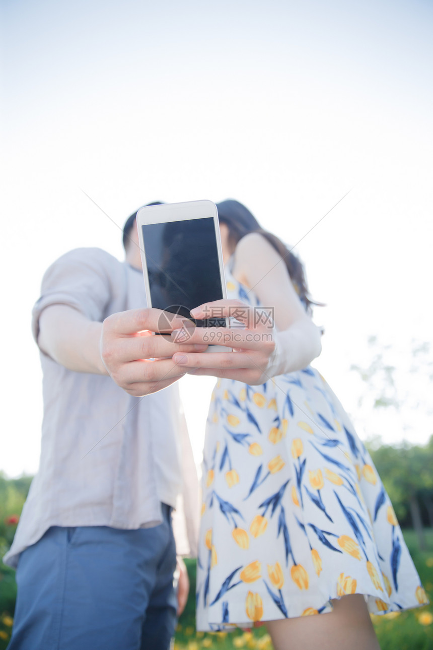 女朋友垂直构图度假青年情侣用手机照相图片