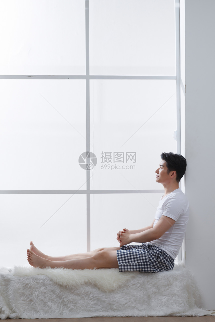 家庭生活住宅内部侧面视角青年男人坐在窗户旁边图片