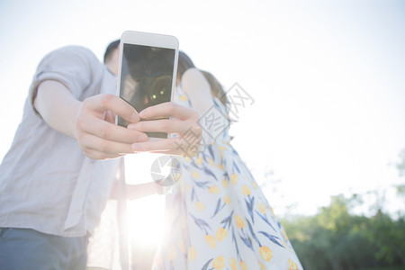 快乐爱日光青年情侣用手机照相图片