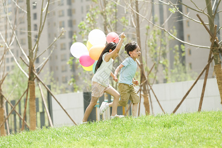 手牵手奔跑的快乐儿童在草地上玩耍图片