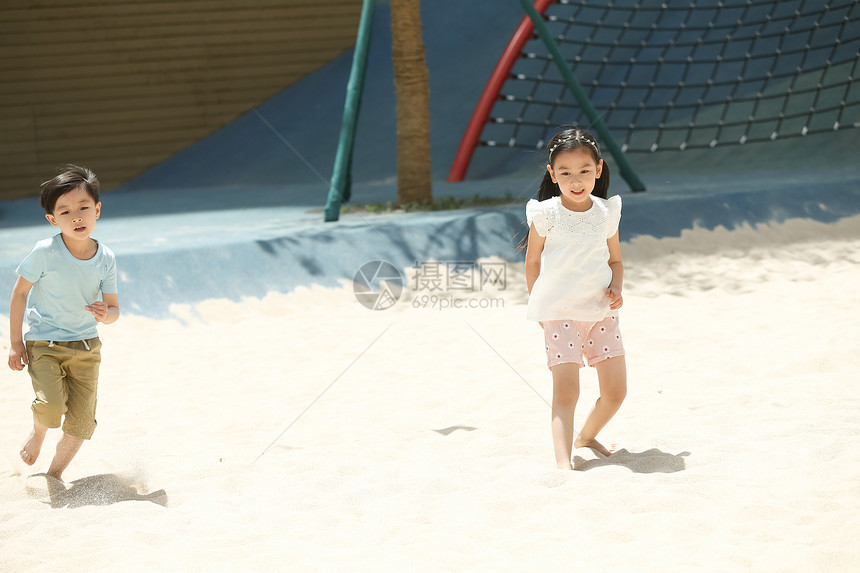 幸福人亚洲人儿童在沙子里踢球图片