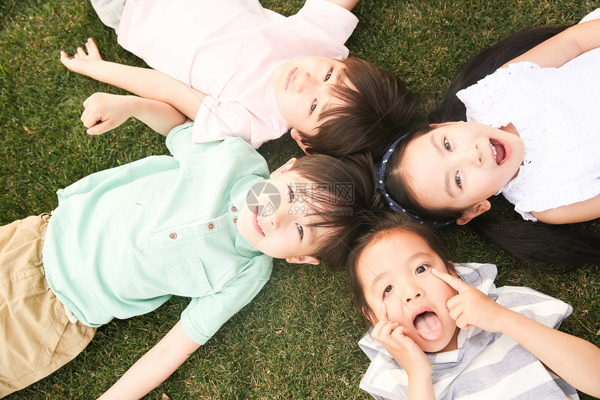 3岁到4岁休闲装仰卧快乐的孩子们在草地上玩耍图片