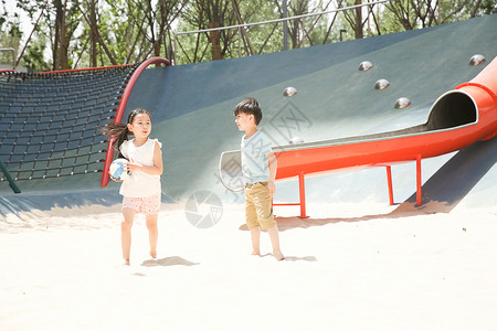 可爱的东方人白昼儿童在沙子里踢球图片