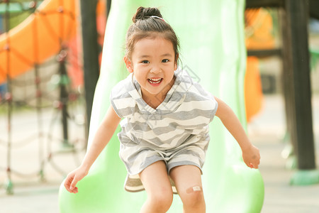 彩色图片学龄前儿童快乐小女孩在户外玩滑梯图片