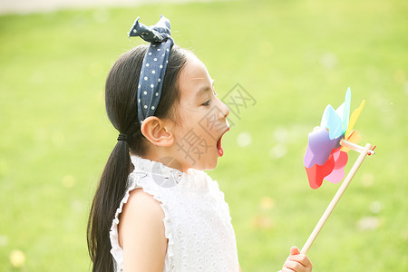 小孩风车不看镜头高兴风车小女孩在户外玩耍背景
