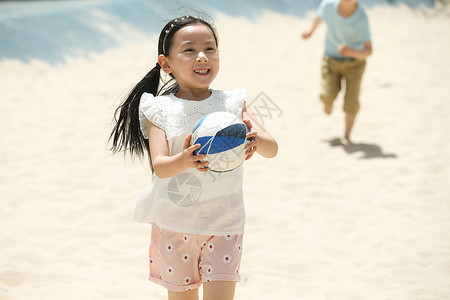 踢球小女孩学龄前儿童赤脚高兴儿童在沙子里踢球背景