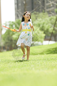 绿色与黄色泡泡好奇心休闲装学龄前儿童小女孩在户外玩耍背景