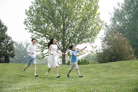 休闲装亚洲人相伴一家三口在草地上奔跑图片