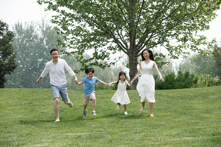 高兴女儿全身像快乐家庭在草地上奔跑图片