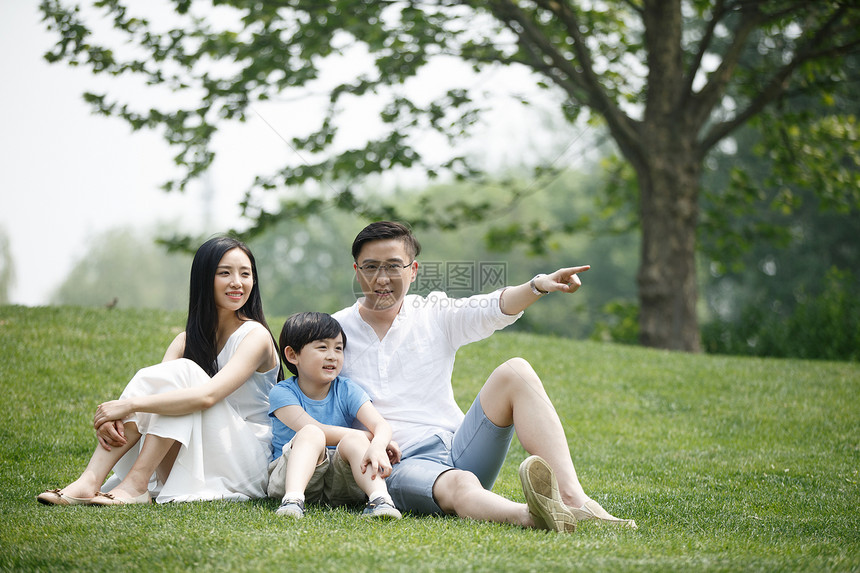 亚洲人公园双亲家庭一家三口坐在草地上图片