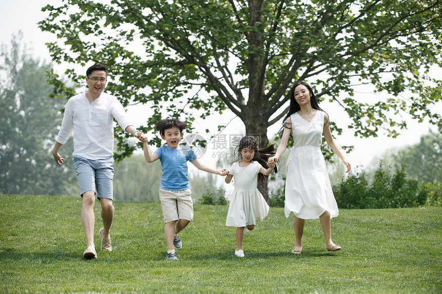 手牵手快乐家庭在草地上奔跑图片
