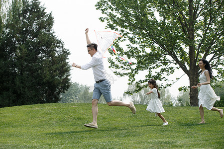 爱奔跑学龄前儿童一家三口在草地上放风筝图片