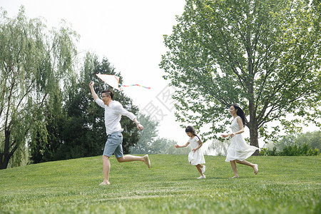 爱青年男人郊游一家三口在草地上放风筝图片