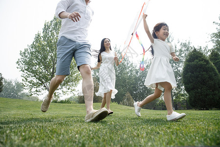 双亲家庭白昼青年女人一家三口在草地上放风筝图片