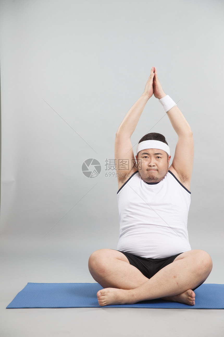 肥胖的青年男人在做瑜伽图片
