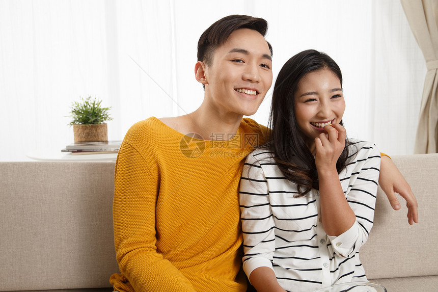 幸福东亚青年夫妇青年情侣坐着沙发上看电视图片