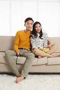 赤脚爱高兴的青年情侣坐着沙发上看电视图片