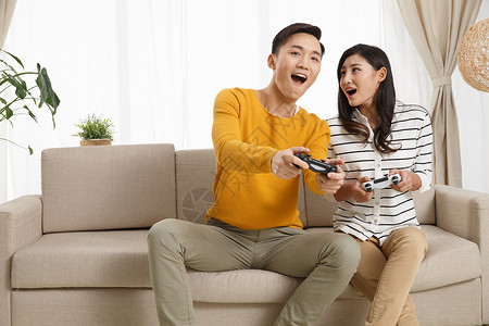 表情亚洲人相伴青年情侣坐着沙发上玩游戏图片