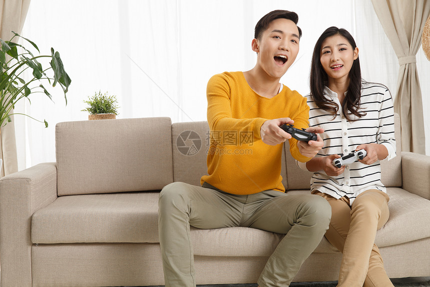 活力无忧无虑仅成年人青年情侣坐着沙发上玩游戏图片