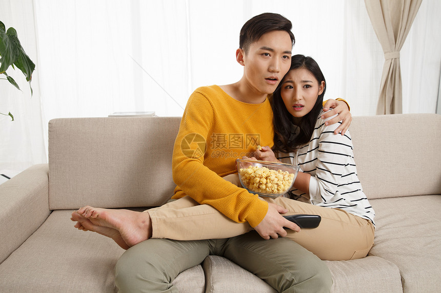 高兴的成年人面部表情青年情侣坐着沙发上看电视图片