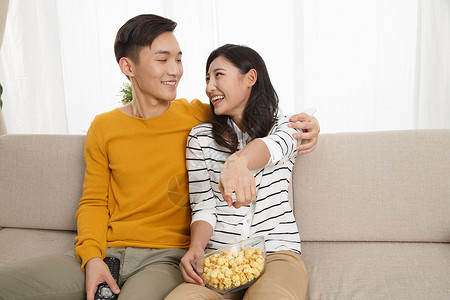 亚洲人乐趣25岁到29岁青年情侣坐着沙发上看电视图片