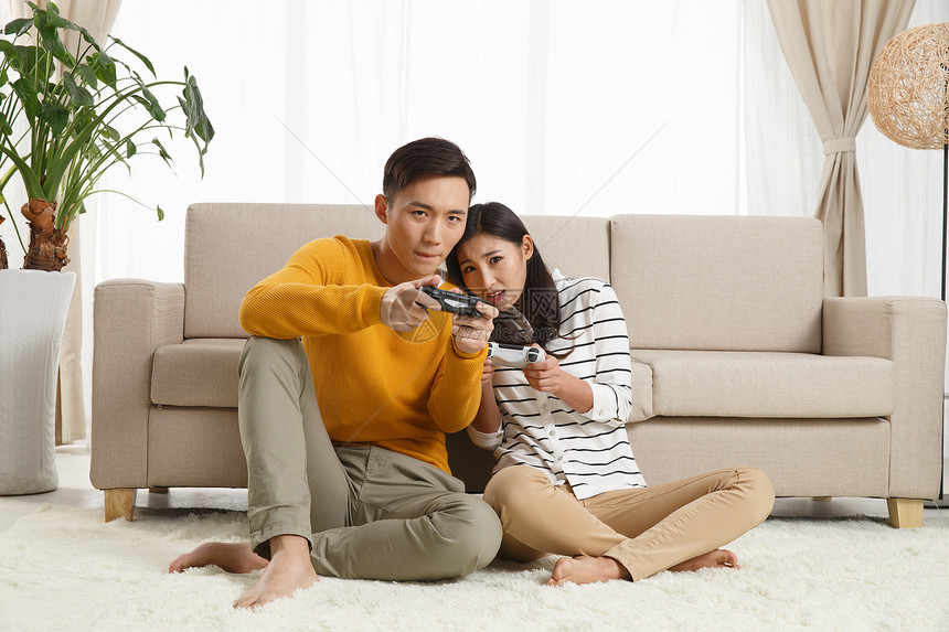 遥控器青年伴侣仅成年人青年情侣坐着沙发上玩游戏图片