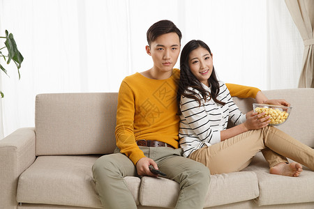 亚洲快乐幸福青年情侣坐着沙发上看电视图片