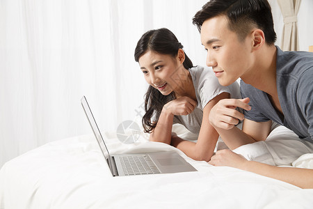 理财使用电脑爱青年情侣趴在床上看电脑图片