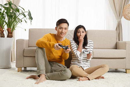东亚休闲装和谐青年情侣坐着沙发上玩游戏图片
