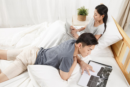 斜靠户内异恋青年男人在床上看书图片