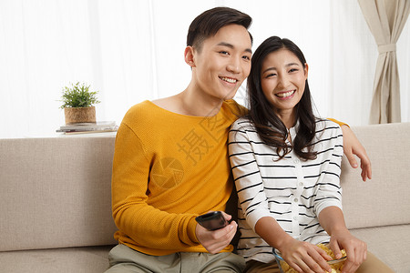 爆米花健康的幸福青年情侣坐着沙发上看电视高清图片