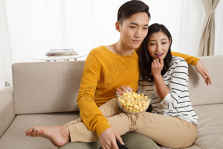 挨着愉悦两个人青年情侣坐着沙发上看电视图片