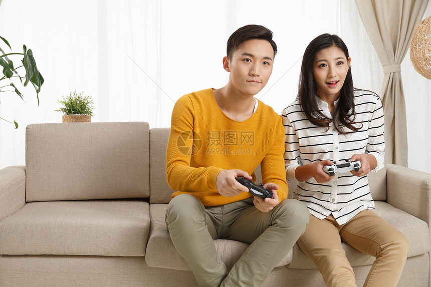 乐趣高兴的青年夫妇青年情侣坐着沙发上玩游戏图片