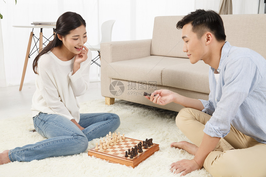 高兴的无忧无虑起居室青年情侣下象棋图片