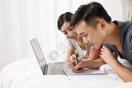 女人幸福爱青年情侣趴在床上看电脑图片