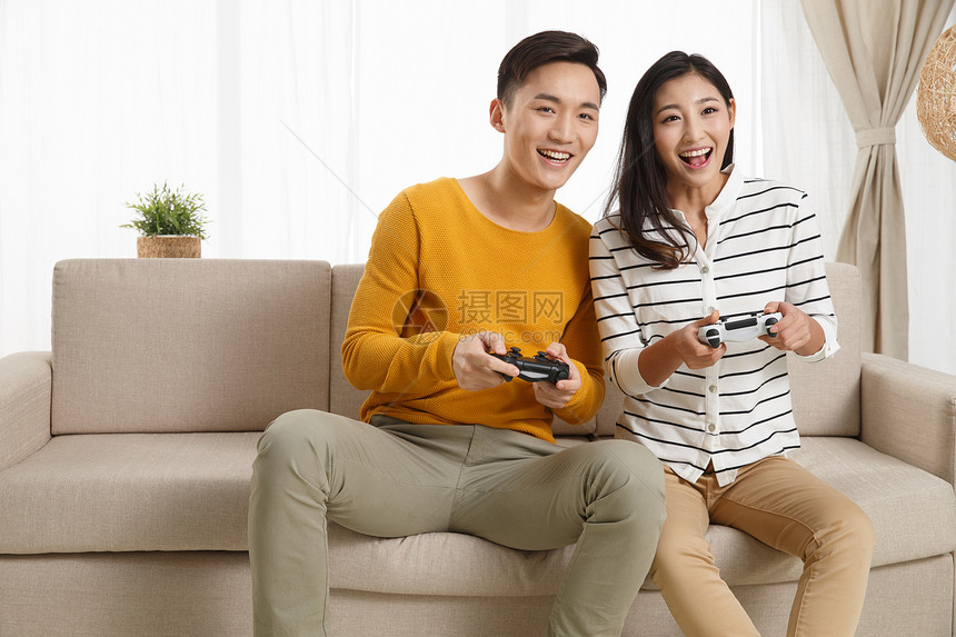 表情爱快乐青年情侣坐着沙发上玩游戏图片