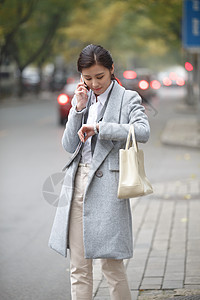 腕表女都市风光现代东方人青年女人在路边等出租车背景