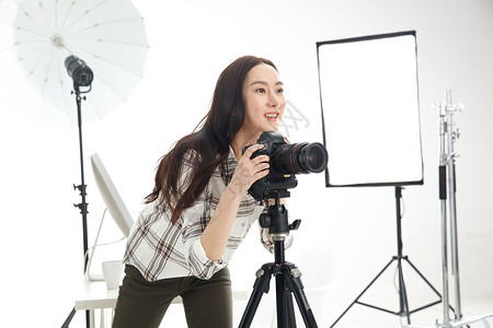 工业摄影师时尚数码相机户内青年女摄影师拿着手机背景