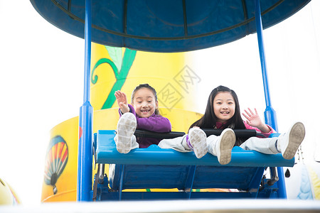 公共游乐设施人愉快旋转类游乐两个女孩在游乐场玩耍背景